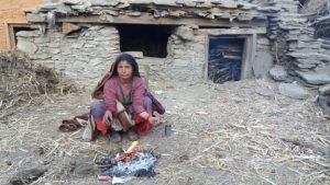 Image caption A menstruating woman crouches outside a mud hut in Krishnamaya's home village