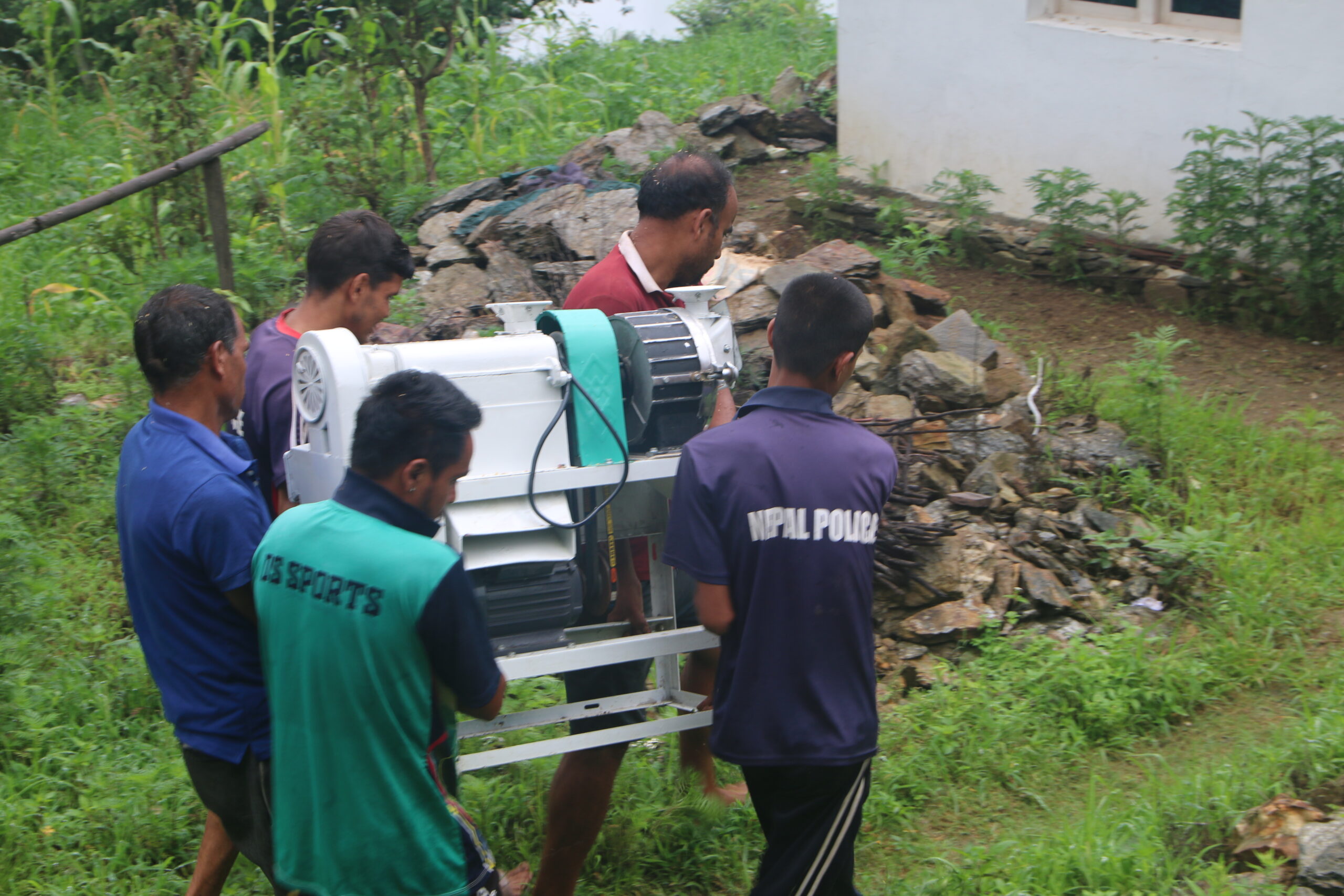 Local men carry the community mill to its installation site in Bhatwada, Achham
